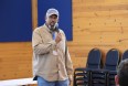 Finis Stribling III speaking into a hand-held mic in a pine-panelled room